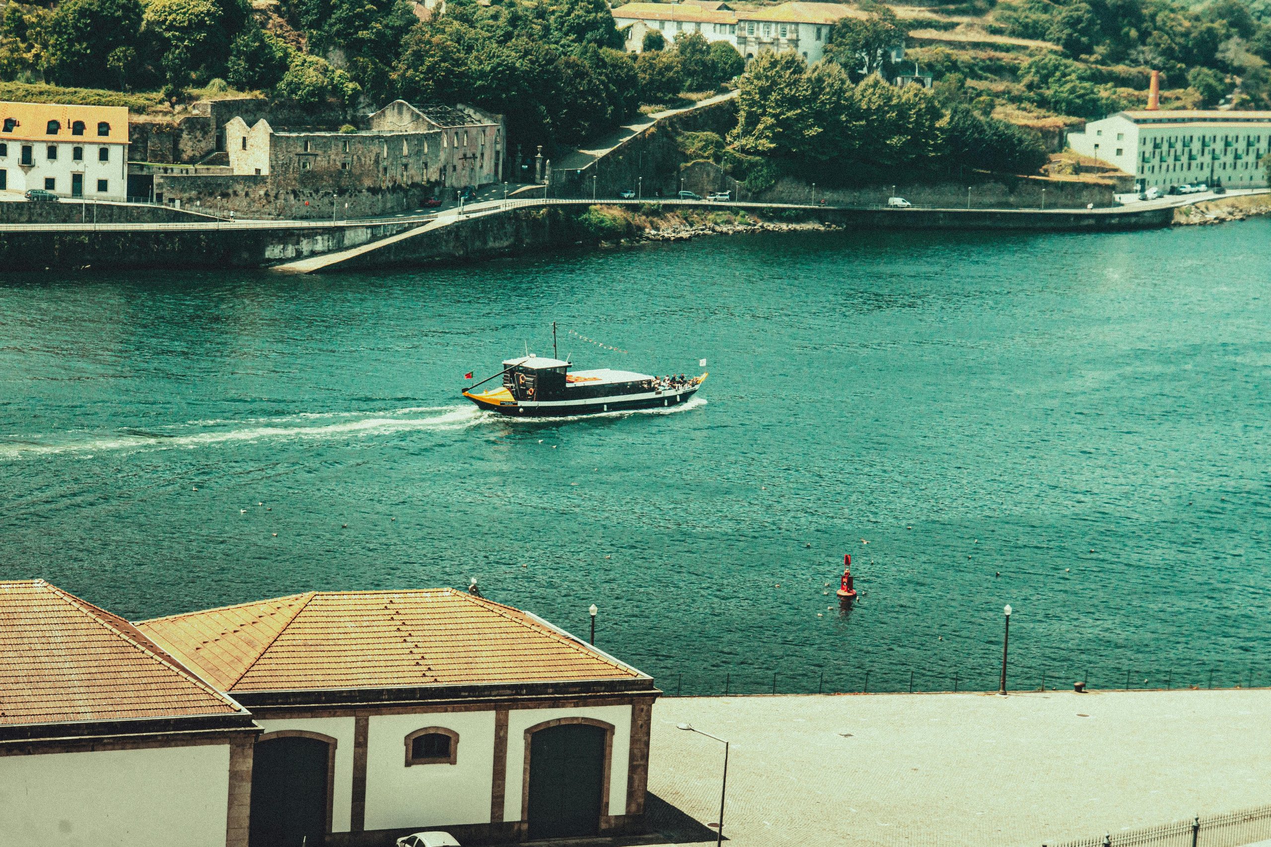 Home Boat cruising on a pristine river with scenic riverside buildings in the backdrop.